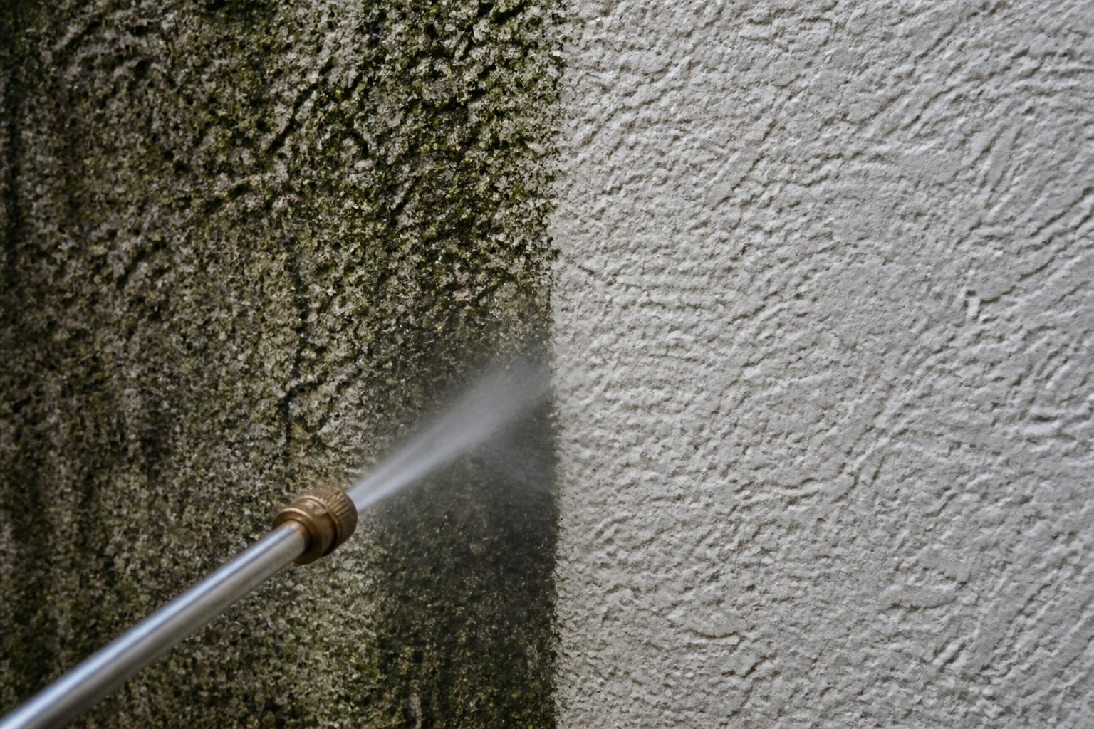 Close-up of stained stucco next to a just-washed stripe